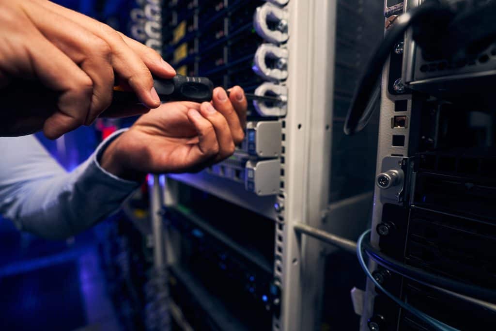 Server Rack Mount - Cropped photo of data center engineer tightening screw on installed equipment using screwdriver